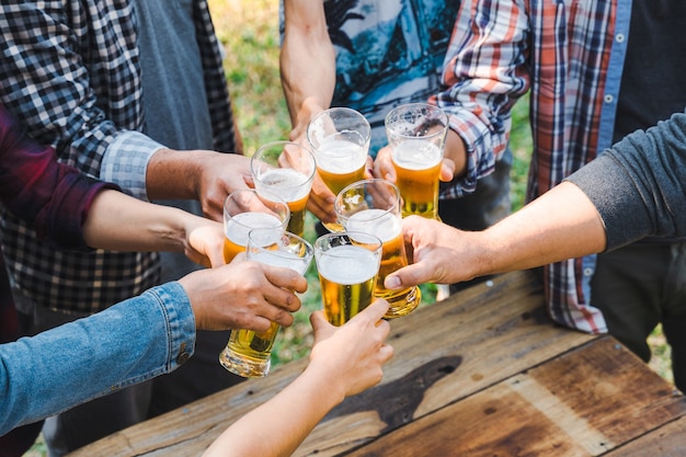 Friends clinking bottle of beer during camping outdoor