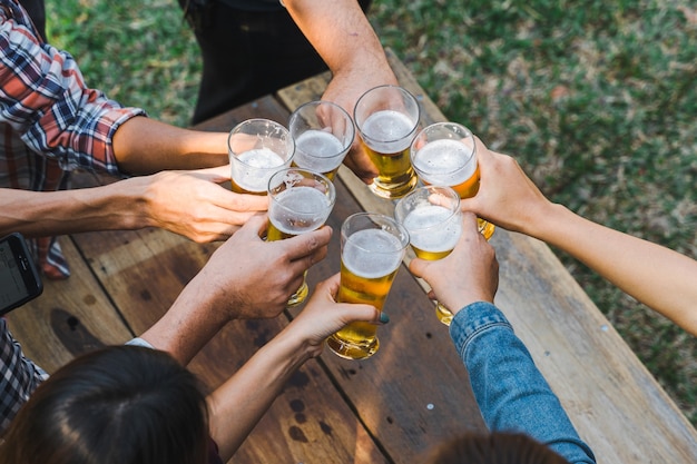 Friends clinking bottle of beer during camping outdoor