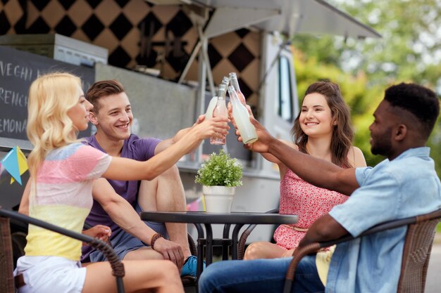 Foto amici che fanno clink con le bottiglie di bevande al camion del cibo