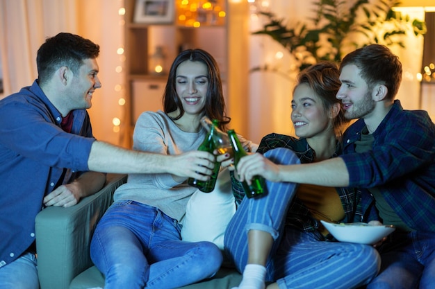 friends clinking drinks at home in evening