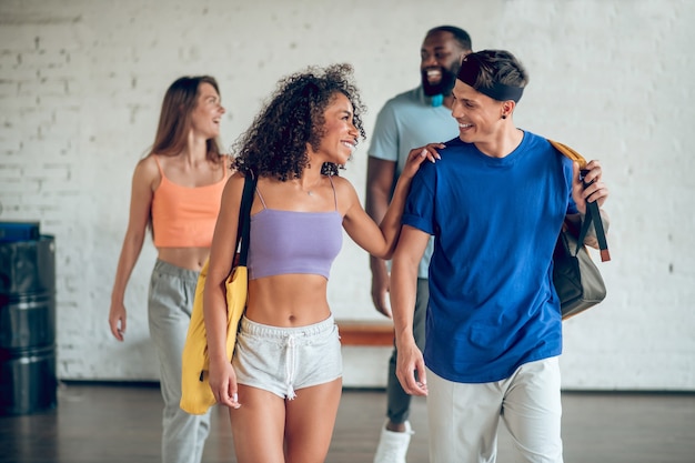 Friends, communication. Group of cheerful cute young people in sportswear with bags walking  communicating