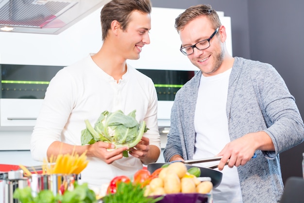 Friends cooking vegetables and meat in domestic kitchen