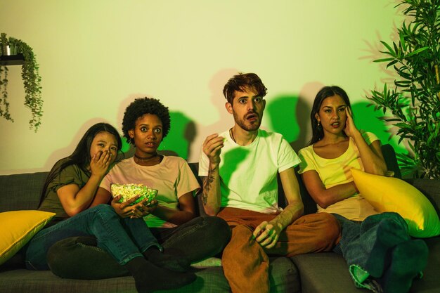 Friends on a couch with shocked faces while watching a scary movie