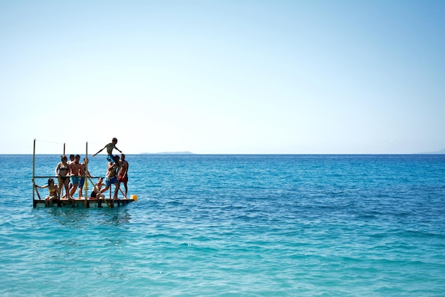 Photo friends on diving platform in sea against clear sky