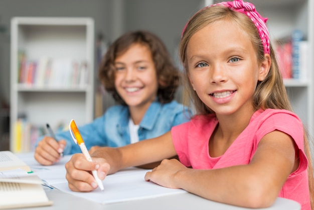 Foto amici che fanno i compiti insieme in biblioteca