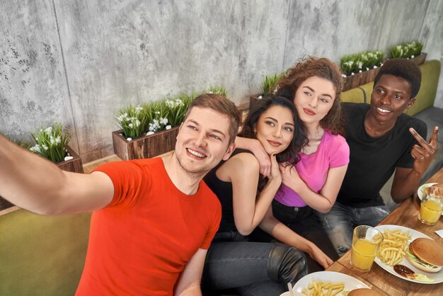 Photo friends doing selfie, sitting together in cafe.