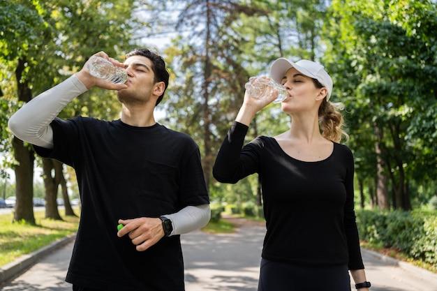 Друзья пьют воду, женщина и мужчина отдыхают, бегают вместе, занимаются фитнесом в спортивной одежде.