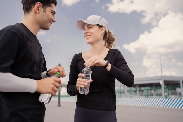 Friends drink water woman and man break fitness run together fitness workout in sportswear