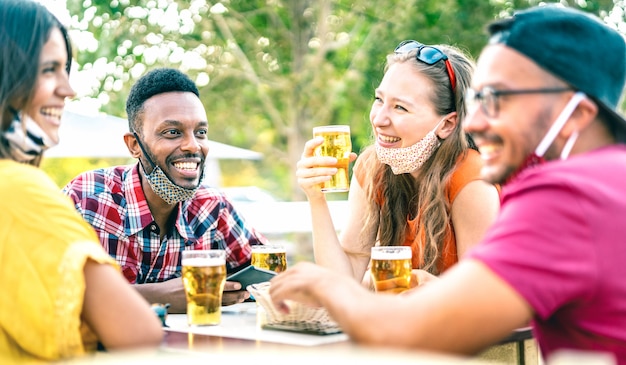 開いたフェイスマスクでビールを飲む友人-左の男にセレクティブフォーカス