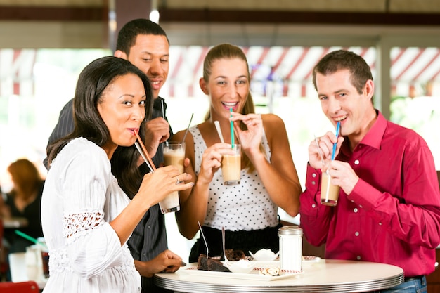 Amici che bevono caffè al latte e che mangiano torta