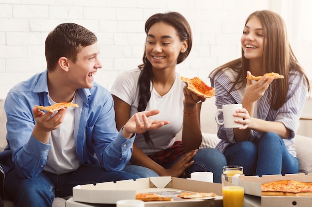 Friends eating pizza and talking at home