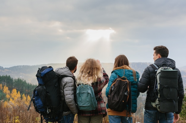 Friends enjoy the sun's rays shining through the clouds in the mountains