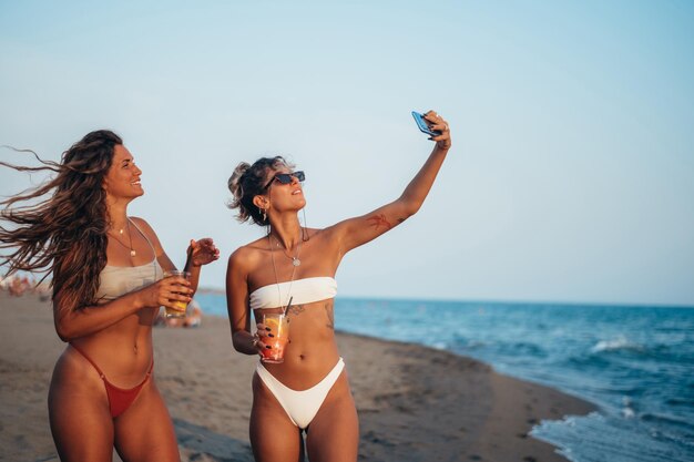 Friends enjoying vacation together and taking selfie on the beach using smartphone