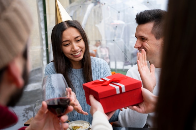 Photo friends exchanging gift during a reunion while having lunch