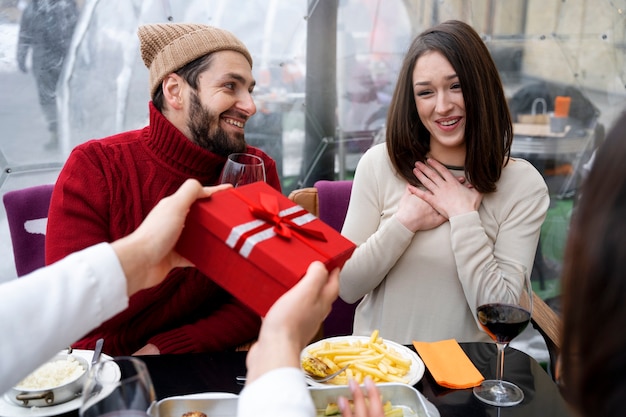 Photo friends exchanging gift during a reunion while having lunch