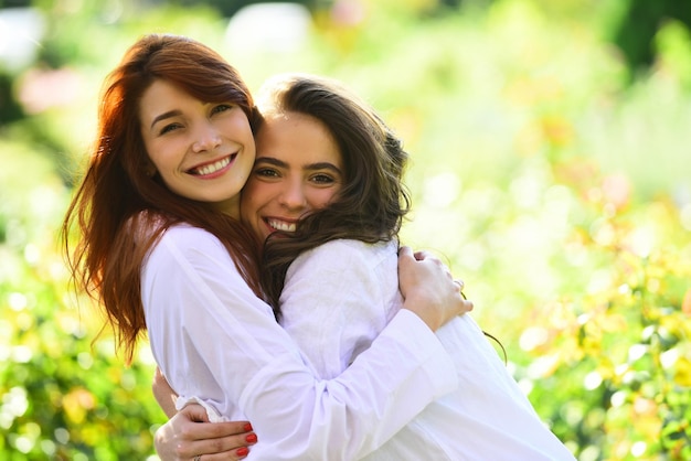Друзья навсегда две милые прекрасные подруги позируют с улыбкой на зеленом весеннем фоне