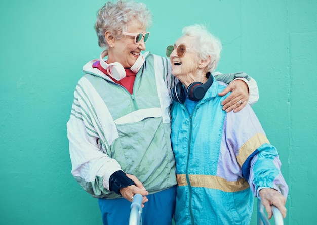 Friends funky and retirement with a senior woman pair outdoor together on a green wall background Happy trendy and fashion with a mature female and friend bonding outside for fun or lifestyle