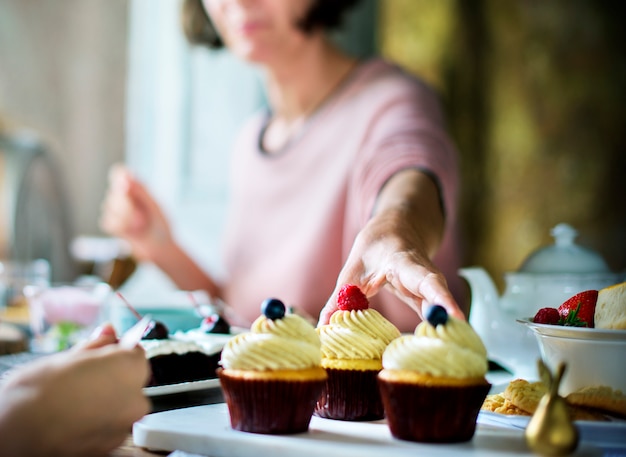 Amici che si riuniscono insieme su tea party eating cakes enjoyment happiness