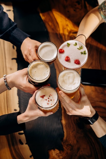 Friends hands toasting and having fun together drinking beer and cocktails at happy hour in pub restaurant Social life style party time concept