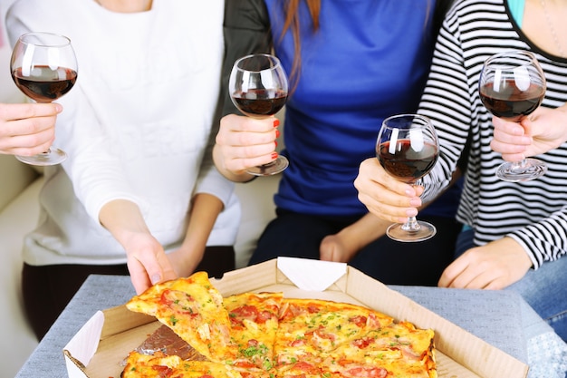 Friends hands with glasses of wine and pizza, close up