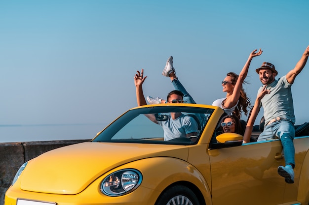 The friends have fun traveling by a cabriolet