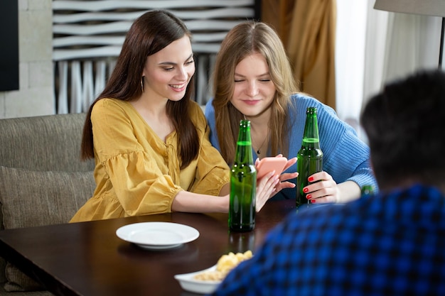 バーで飲み物を飲んでいる友人彼らはビールとピザと一緒に木製のテーブルに座っています