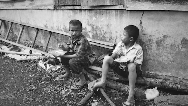 Photo friends having food while sitting against wall