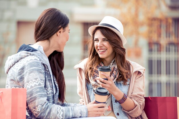 Friends having fun and drink coffee to go after shopping