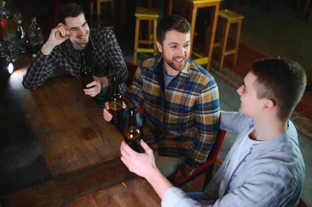 Foto amici che si divertono giovani uomini felici in abbigliamento casual che bevono birra nel pub