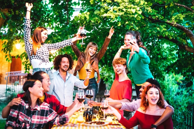 Friends having fun outdoor toasting red wine at garden party