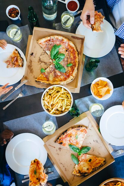 Foto amici che mangiano pizza e patatine fritte