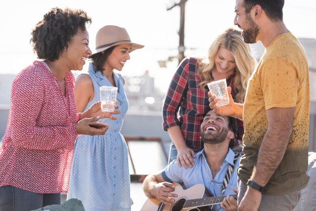 Friends having a rooftop party and playing guitar