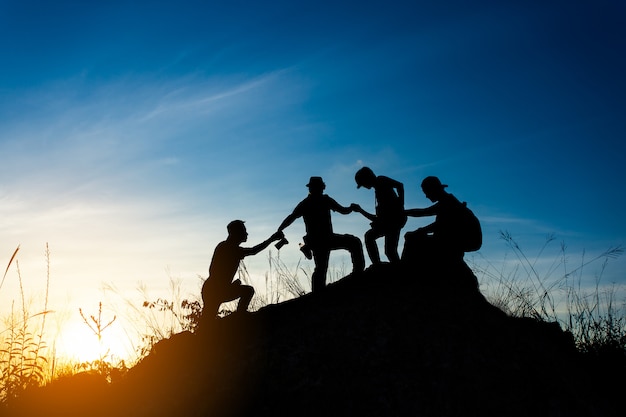 Photo friends helping each other and with teamwork trying to reach the top of the mountains