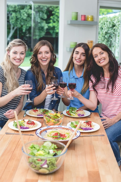 friends holding glass of red wine while having meal