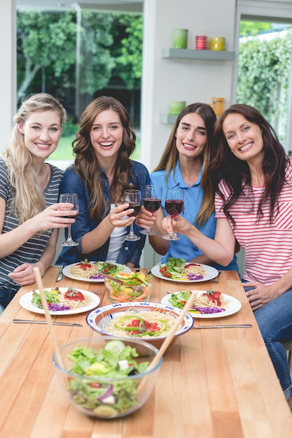 Photo friends holding glass of red wine while having meal