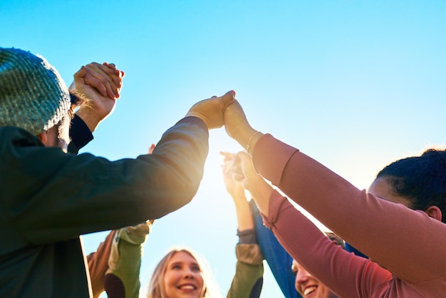 Friends holding hands and happy in nature for celebration bonding and positive energy Students gesture and smile in circle for support victory and achievement on trip for reunion or vacation