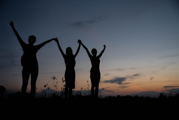 Photo friends holding hands up at sunset.