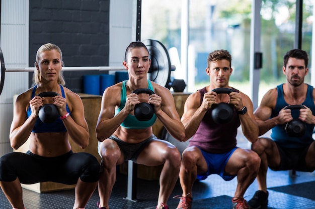 Photo friends holding kettlebells in gym