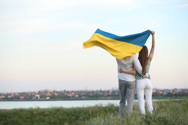 Friends holding national flag of Ukraine in field back view Space for text