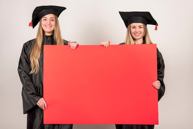 Foto amici che tengono cartello rosso alla laurea