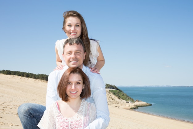 Friends holidays man and two girl in summer beach vacation play on sand dunes