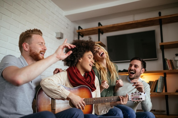 Friends at home enjoying singing and playing guitar