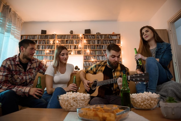 Friends on a house party playing guitar having fun