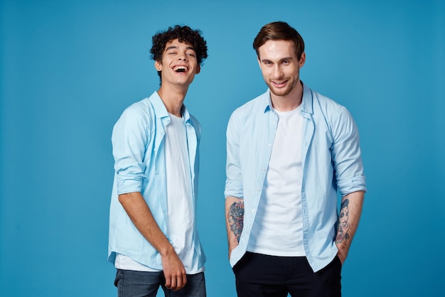 Friends in identical clothes on blue background gesturing with hands cropped view