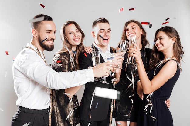 Фото Друзья в стильной элегантной одежде вместе улыбаются, держа в руках бокалы с шампанским