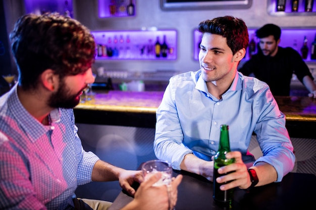 Friends interacting with each other at bar counter and having beer