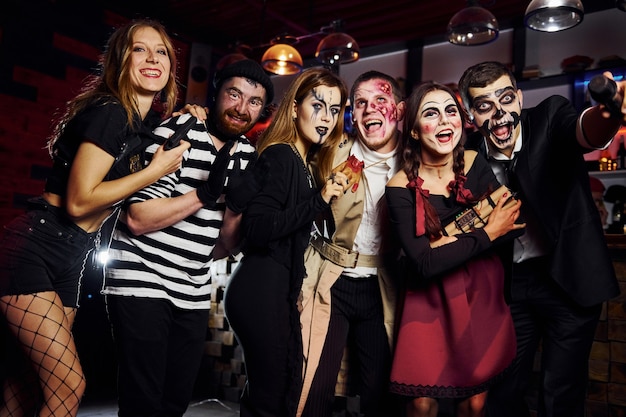 Friends is on the thematic halloween party in scary makeup and costumes have fun and posing for the camera together.