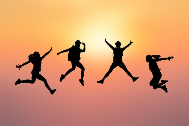 Friends jumping against sky during sunset