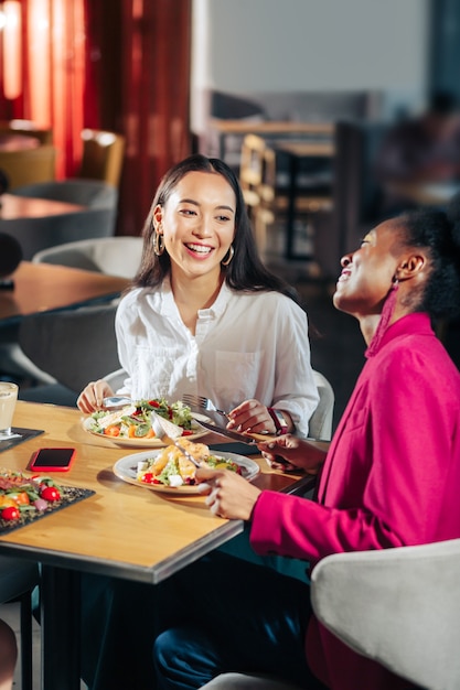 Friends laughing Best cheerful friends laughing while communicating in restaurant