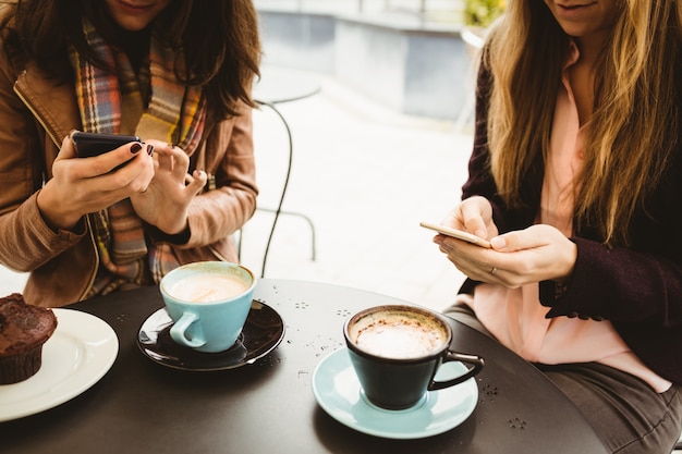 カフェでスマートフォンを見ている友人